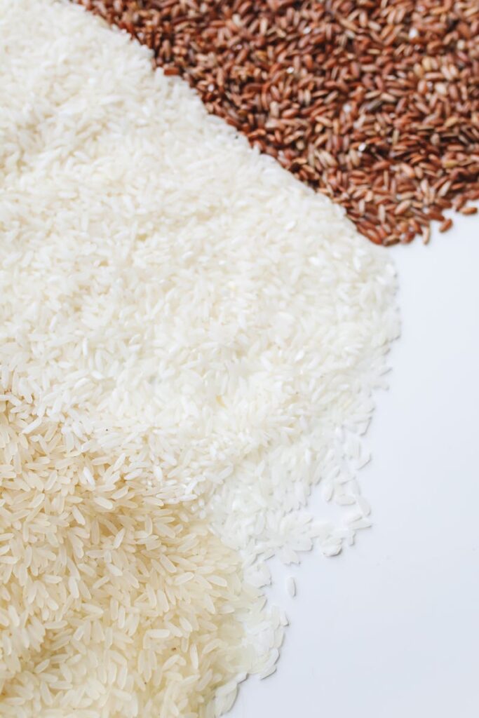 Close-up of assorted uncooked rice demonstrating diversity in grain types on a white background.